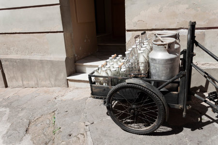 Bottles and aluminum cans of milk for delivery in vintage rusty milkman bicycle.