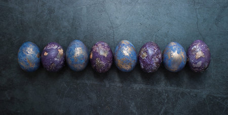 Easter card with a copy of the place for the text. Purple, blue and golden eggs on a dark...