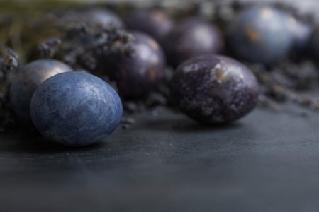 Easter card with a copy of the place for the text. Purple, blue and golden eggs with lavender on a dark background. The purple hue trend of 2022 is very relevant. Natural dye karkade tea. top view.の写真素材