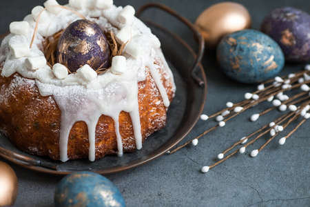 Easter card with a copy of the place for the text. Purple, blue and golden eggs with a cake on a dark background. The purple hue trend of 2022 is very peri. Natural dye karkade tea. top view.の写真素材