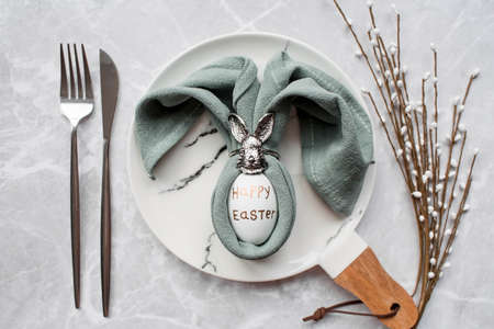 Banner. table setting. A fashionable marble plate with a rabbit and an egg in a napkin on a gray background. top view. Happy Easter holiday concept for cafes and restaurants.の写真素材
