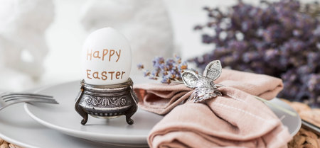 table setting. A plate of Easter eggs, rabbits, lavender and a napkin with appliances on a white...