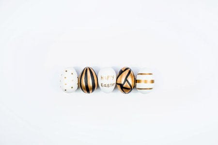 Golden, black, white Easter eggs on a white background. geometry. minimal concept. top view. A card with a copy of the place for the text.の写真素材