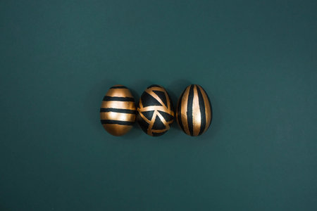 Gold, black, white eggs on a trendy emerald background. geometry. The minimal concept. top view. An Easter card with a copy of the place for the text.の写真素材