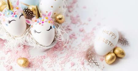 Banner. Easter eggs in the form of a unicorn, and with a gold pattern on a white background. flat lay. Copy space for text.の写真素材