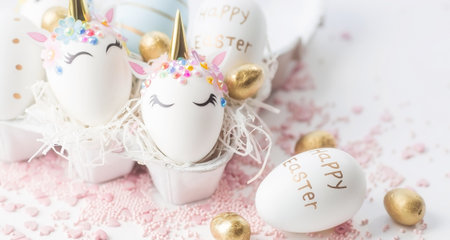 Banner. Easter eggs in the form of a unicorn, and with a gold pattern on a white background. flat lay. Copy space for text.の写真素材