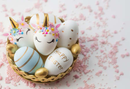 Banner. Easter eggs in the form of a unicorn, and with a gold pattern on a white background. flat lay. Copy space for text.の写真素材