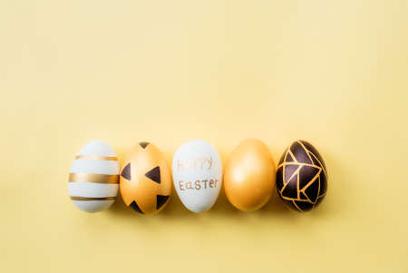 Golden, black, white easter eggs on a yellow-black background. geometry. minimal concept. View from above.Card with copy space for text.の写真素材