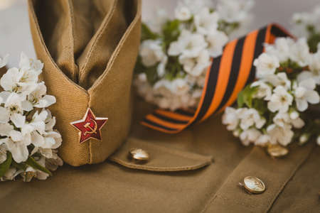 Banner for May 9. A military uniform, a cap with a star, a St. George ribbon and a cherry blossom in the background. The concept of the Great Victory Day 941-1945 and Defender of the Fatherland Day.の写真素材