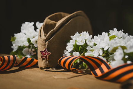 Banner for May 9. A military uniform, a cap with a star, a St. George ribbon and a cherry blossom in...