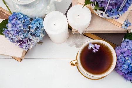 A visual content. Still life in vintage style. A mug with a drink, an old book, a cage, candles and...