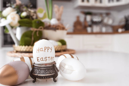 An iron pot with Easter eggs. In the background is a white Scandinavian-style kitchen, flowers and...