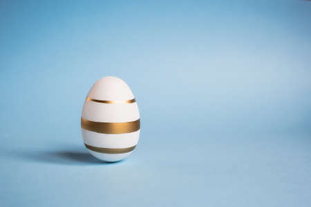 Easter painted eggs isolated on trendy blue background. The minimum concept. Card with copy space for text.の写真素材