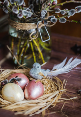 Pink and yellow Easter eggs in nest on wooden background. Minimal easter concept. Easter card with...