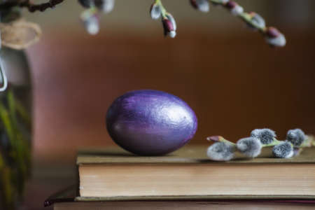 A bouquet of willow and Easter eggs in a nest on a wooden background. The concept of a happy bright Easter.の写真素材