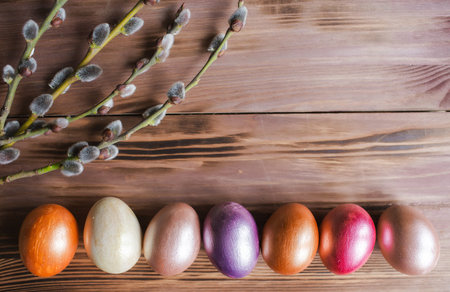 Colorful Easter eggs and willow branches on a wooden background.