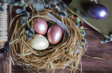 Pink and yellow Easter eggs in nest on wooden background. Minimal easter concept. Easter card with...