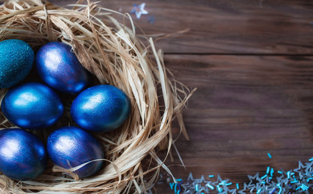 Blue Easter eggs in nest on wooden background. Minimal easter concept. Easter card with copy space...