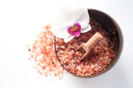 spa treatments. Himalayan salt and orchid flower in a cup of natural coconuton a white background, top view. beauty and health concept.の写真素材