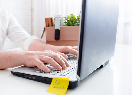Dismissal from work and job search. Computer keyboard, sticker with the words job search and male...