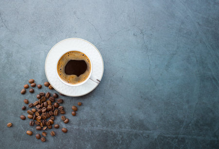 cafes and restaurants. A mug of invigorating, black coffee and coffee beans on dark gray background....