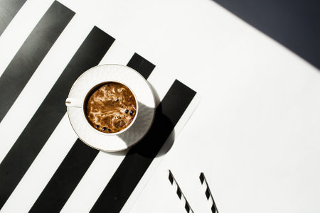 Cup of coffee on a black and white striped background. Top view.の写真素材