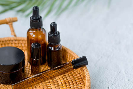 aromatherapy. A rattan tray held a glass bottle with a pipette for oil, lotion, cream, a massage brush, and a palm leaf. Natural organic eco-cosmetics. Layout of the beauty salon branding.の写真素材