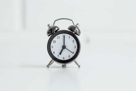Black retro alarm clock on a white brick wall background. The concept of good morning time.の写真素材