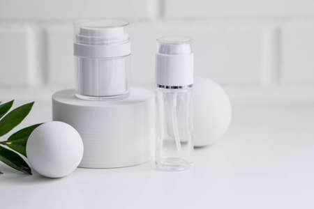 Glass white bottles on the podium for oil, lotion, cream on the background of a brick wall. natural cosmetics. Layout of the beauty salon branding.の写真素材