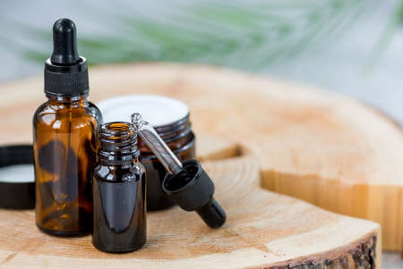 aromatherapy. On a wooden stand was a glass bottle with a pipette for oil, lotion, and a palm leaf. Natural organic eco-cosmetics. Layout of the beauty salon branding.の写真素材