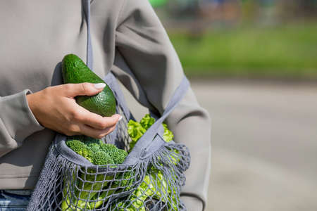 A woman's hand with an ecological shopping bag, buying vegetables, isolated on a white background. A copy of the place for the text.の写真素材