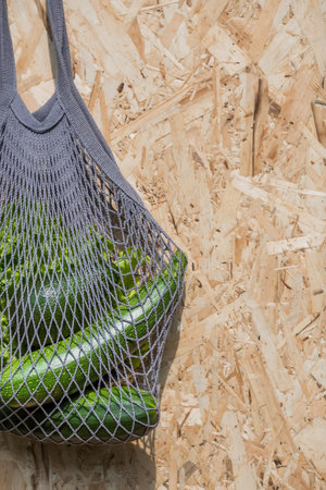 A woman's hand with an ecological shopping bag, buying vegetables, isolated on a white background. A...