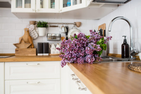 A beautiful purple and lilac bouquet on the kitchen countertop. In the background-the interior of a...