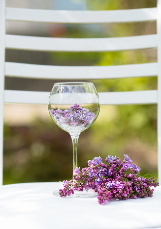 Beautiful still life, spring card. Purple lilac lies in a glass, surrounded by flowers and wicker baskets.の写真素材