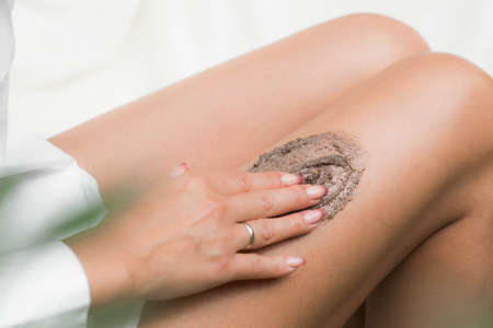 Closeup woman legs with coffee massage scrub. Cosmetology, grooming, Spa cosmetic products, beauty and bikini concept.の写真素材