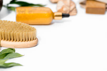 Cosmetology, peeling, spa cosmetic products, beauty concept.Natural ingredients for home skin care.Organic wooden brush for dry anti-cellulite massage, bottle with dispenser on white background.の写真素材