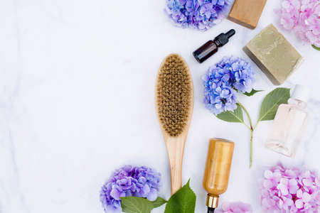 Cosmetology, peeling, Spa cosmetics, beauty concept. Natural ingredients for home skin care. Anti-cellulite massage brush, bottle with dispenser, soap and hydrangea flowers on a white background.の写真素材