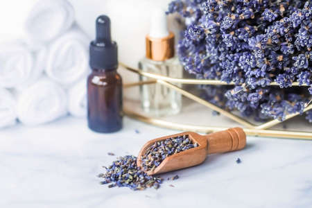 natural lavender herb. Lavender oil bottle, candle and white towels on a white marble background. Place for an inscription. beauty and health concept.の写真素材