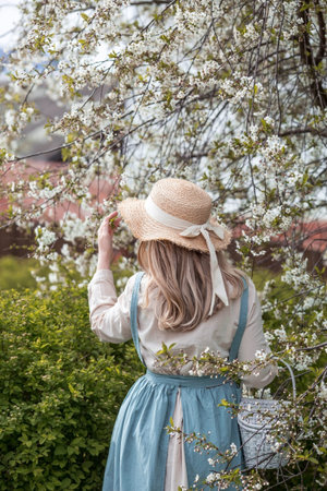 vintage. A beautiful, young woman in retro clothes and a straw hat in a blooming cherry orchard....
