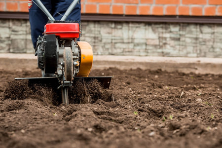 Man Farmer plows the land with a cultivator. Agricultural machinery: cultivator for tillage in the...