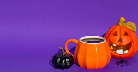 Halloween pumpkins with a cup of coffee on a purple backgroundの写真素材
