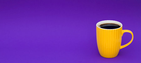 Yellow cup of coffee on a purple background. Place for text.の写真素材