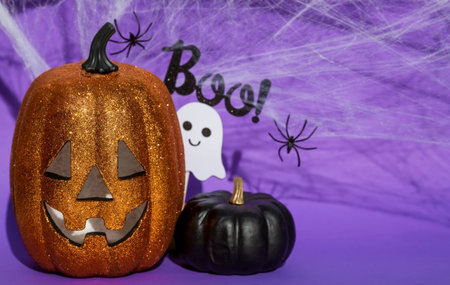 Halloween pumpkin with scary face and spiders on purple background, space for textの写真素材