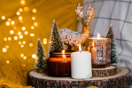 Burning candles and christmas decorations on wooden tray with warm plaid. Winter cozy style. Hygge concept.の写真素材