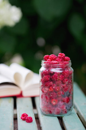 Garden raspberries in a glass cup on a wooden background.Close-up. natural vitamins. The concept of...