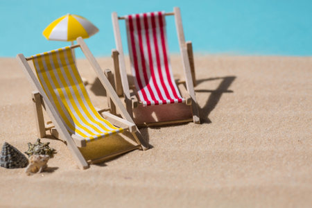 A toy beach chaise longue, seashells, a starfish on white sand with shadows. Sunlight. The concept of the sea, a beach holiday and a resort. summer minimalism.の写真素材