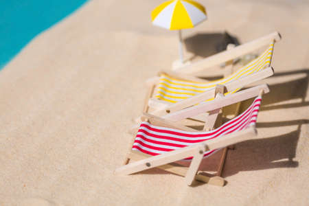 A toy beach chaise longue, seashells, a starfish on white sand with shadows. Sunlight. The concept of the sea, a beach holiday and a resort. summer minimalism.の写真素材