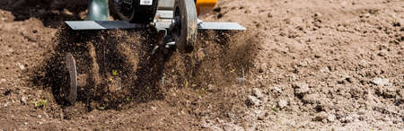 Banner. A male farmer plows the land with a cultivator. Agricultural machinery for tillage in the garden, combine harvester.の写真素材