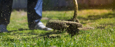 Banner. A human lawn mower cuts the grass in the backyard. Agricultural machinery for the care of...