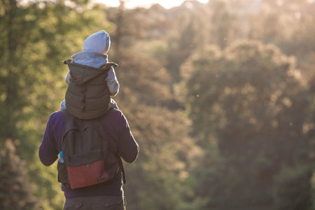 A man and a boy go hiking in the summer forest with a backpack for hiking.Portrait of a father and...